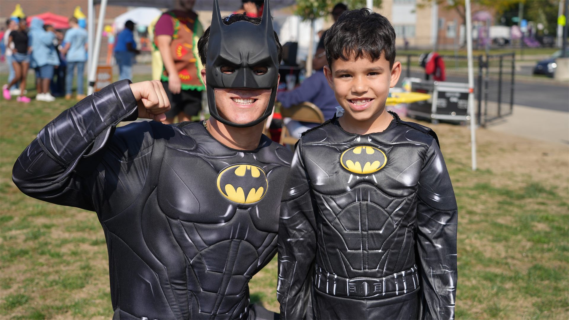 A volunteer and a boy both dressed as Batman